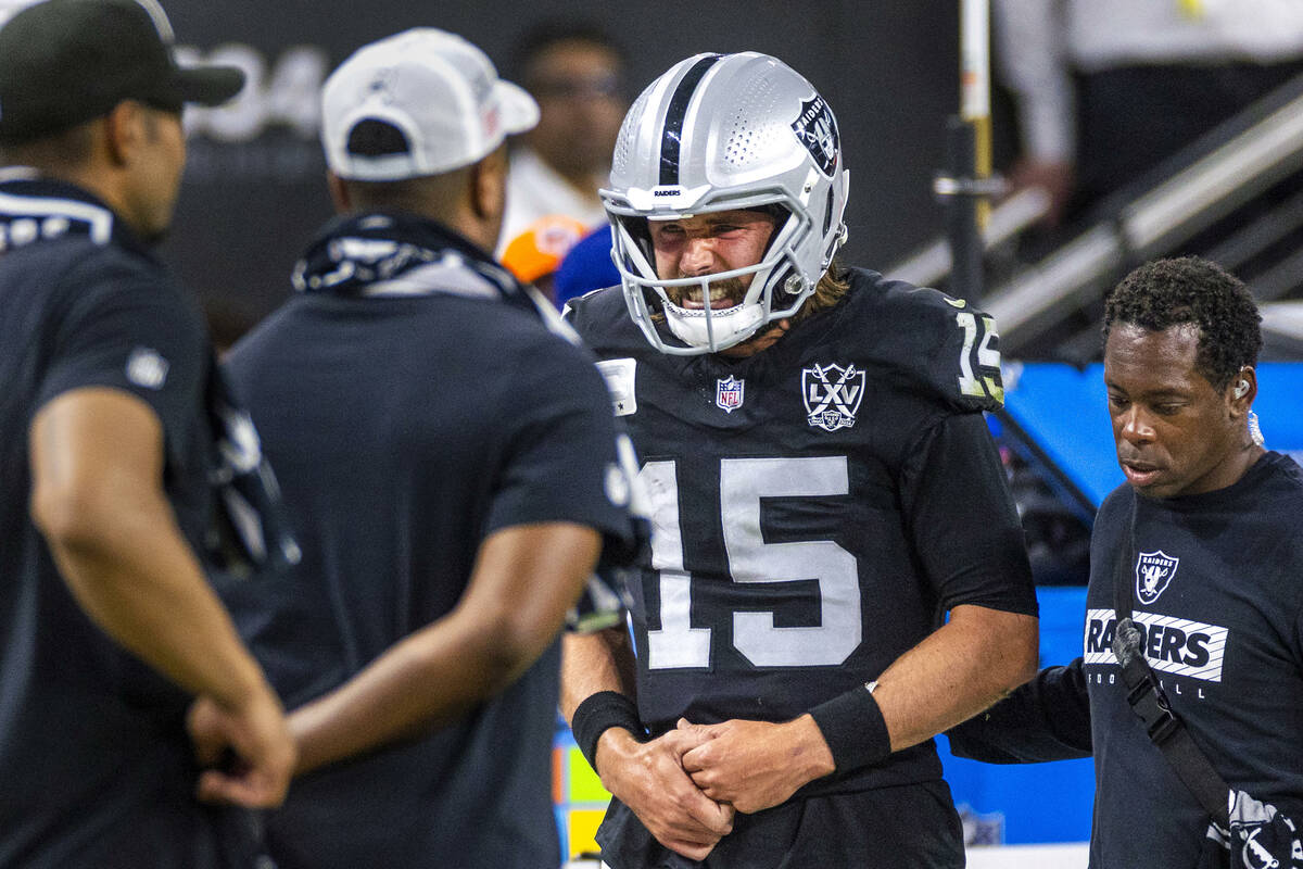 Raiders quarterback Gardner Minshew (15) is escorted off the field after a sack with a hand inj ...