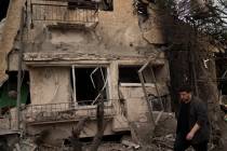 A man walks past a damaged building after a rocket fired from Lebanon hit an area in Rinatya, o ...