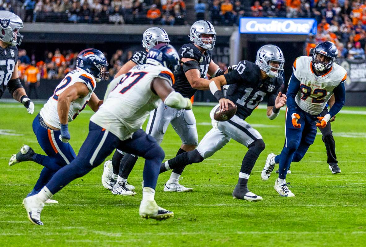 Raiders quarterback Desmond Ridder (10) scrambles to pass Denver Broncos linebacker Dondrea Til ...