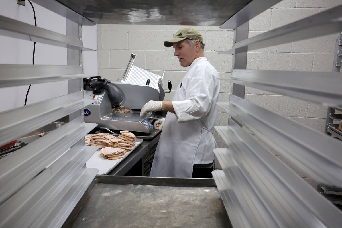 Sous chef Neil Mockovak prepares slices turkey for 700 Thanksgiving meals at Catholic Charities ...