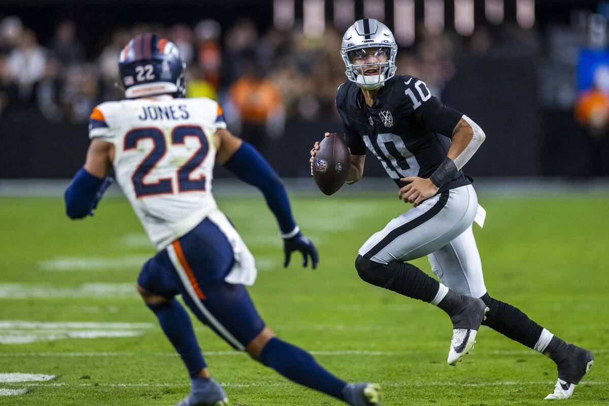 Raiders quarterback Desmond Ridder (10) scrambles to pass as Denver Broncos safety Brandon Jone ...