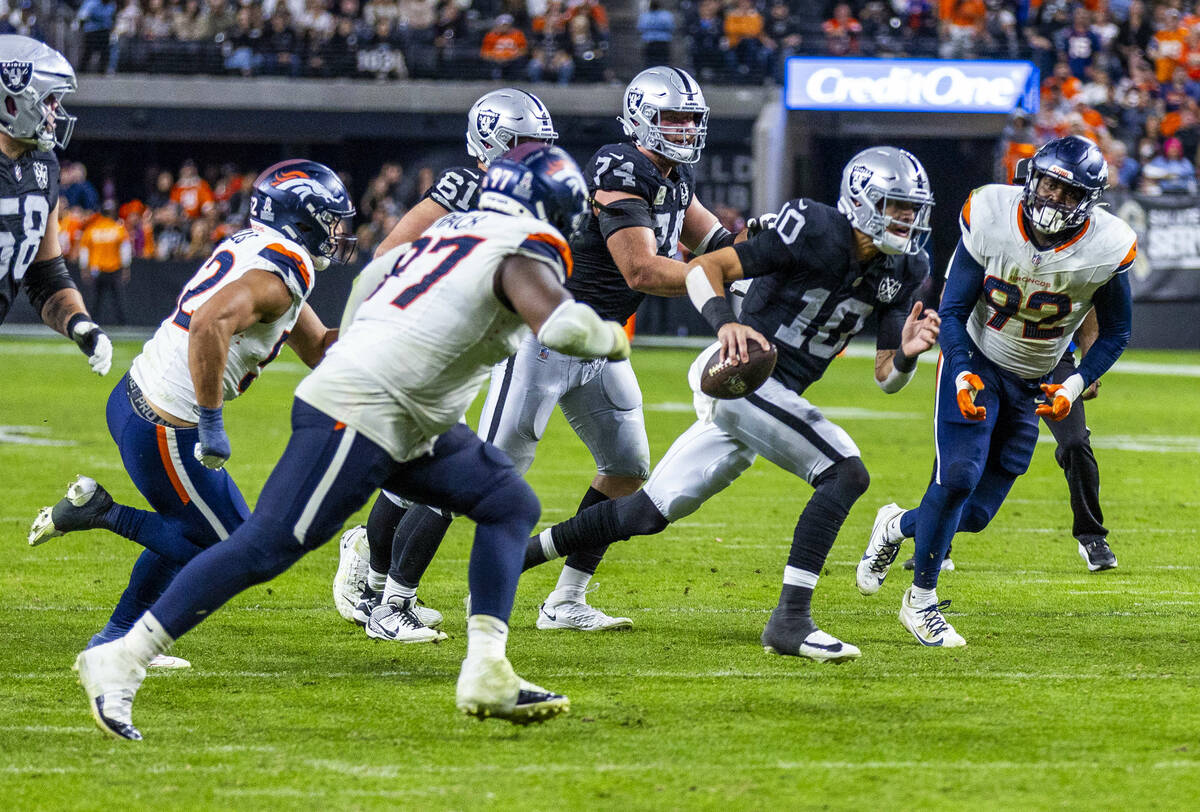 Raiders quarterback Desmond Ridder (10) scrambles to pass Denver Broncos linebacker Dondrea Til ...