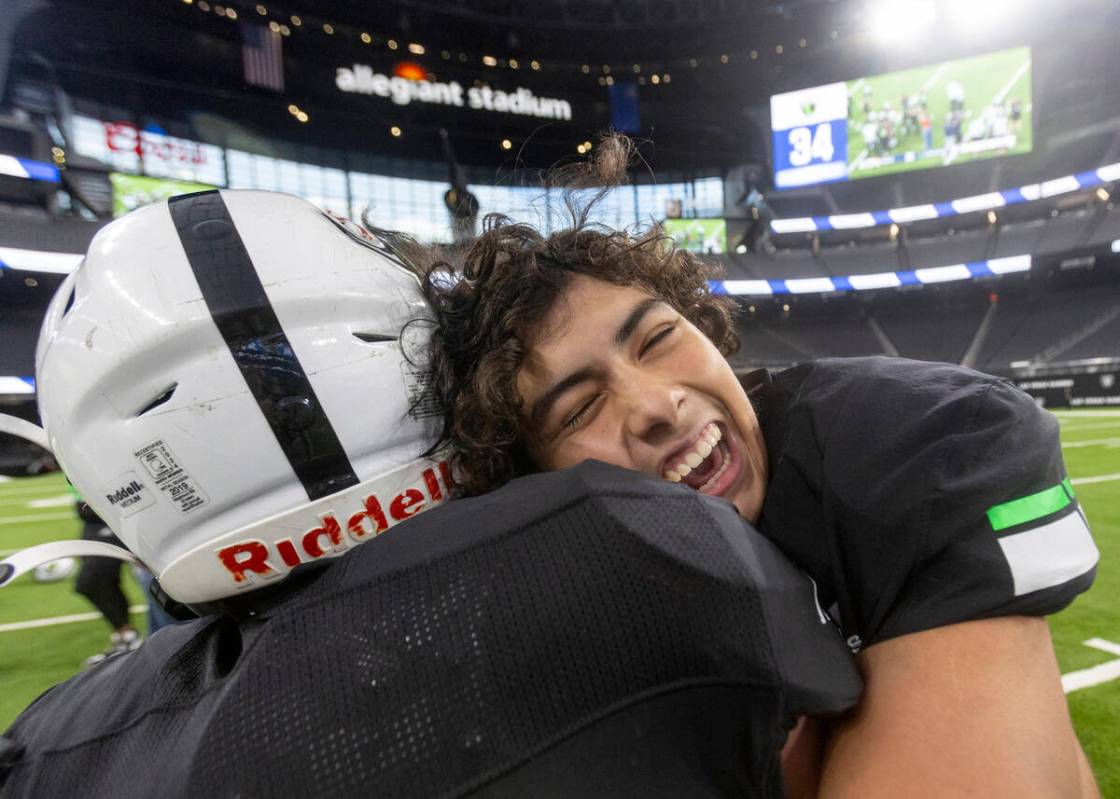 SLAM Academy players hug after winning the Class 3A football state championship game against Tr ...