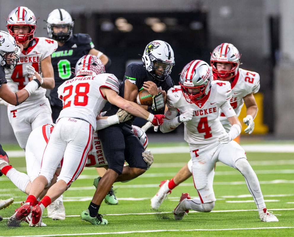 SLAM Academy junior Alaijah Young, center, is tackled during the Class 3A football state champi ...