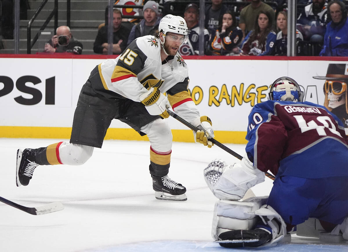 Vegas Golden Knights defenseman Noah Hanifin, back, puts a shot on Colorado Avalanche goaltende ...