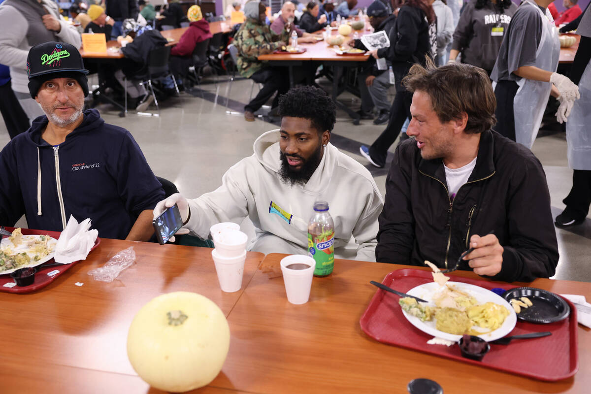 Raiders cornerback Nate Hobbs, center, shows Michael Grant, 47, right, how Grant's team (the Ch ...