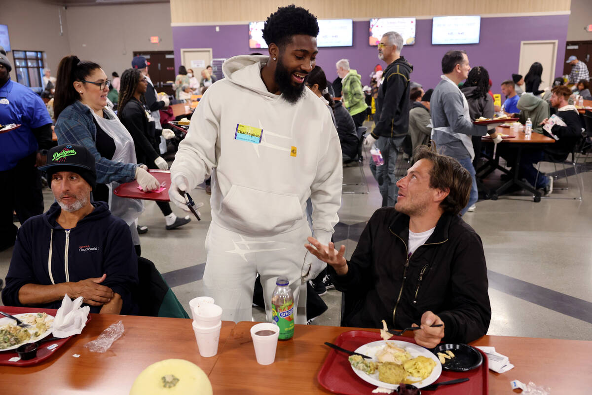 Raiders cornerback Nate Hobbs, center, shows Michael Grant, 47, right, how Grant's team (the Ch ...