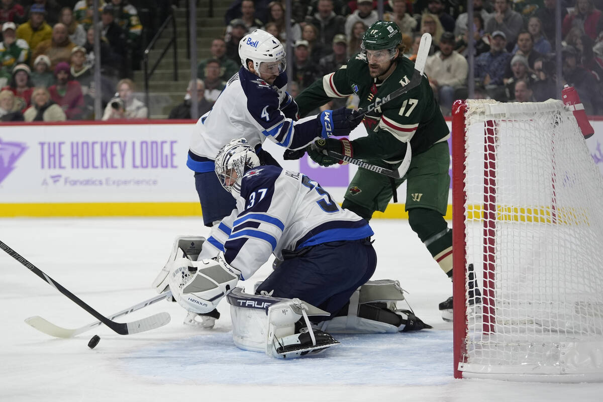 Winnipeg Jets goaltender Connor Hellebuyck (37) stops a shot during the first period of an NHL ...