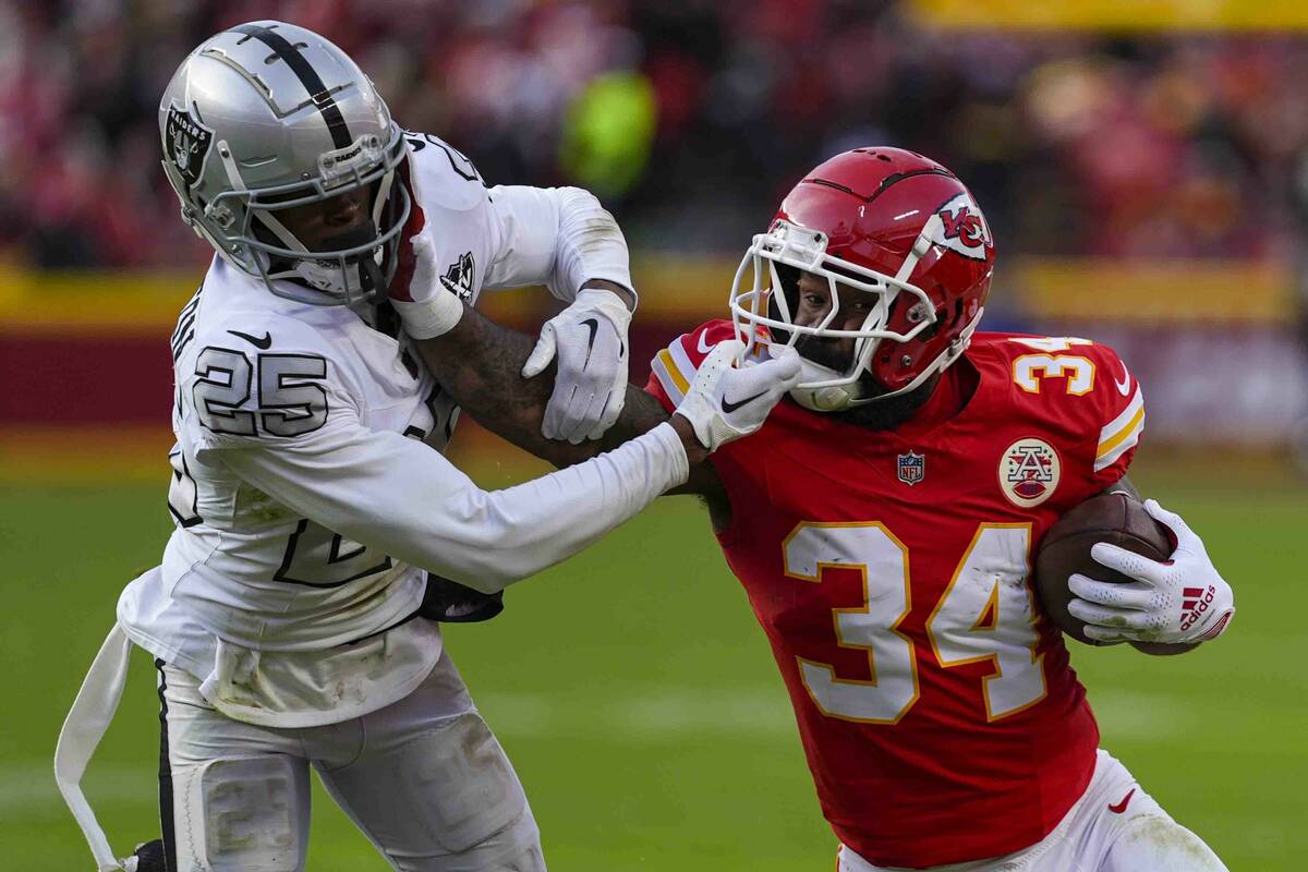 Kansas City Chiefs running back Samaje Perine (34) tries to hold off Las Vegas Raiders cornerba ...