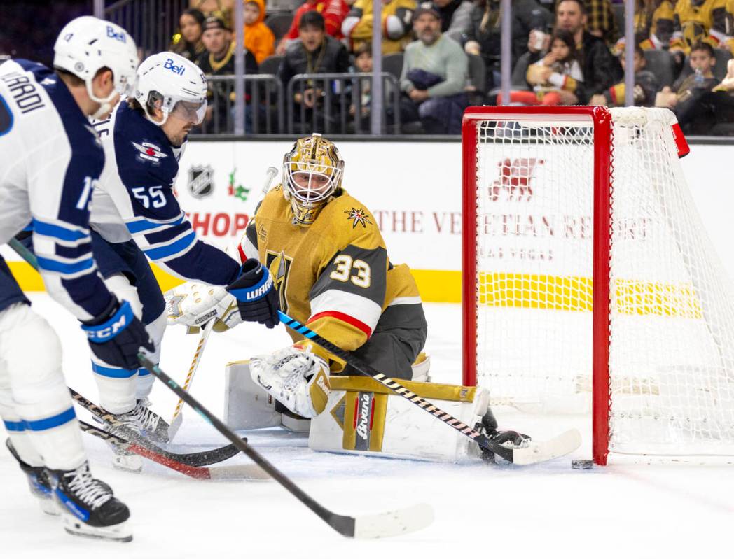 Golden Knights goaltender Adin Hill (33) barely blocks a shot by Winnipeg Jets center Mark Sche ...