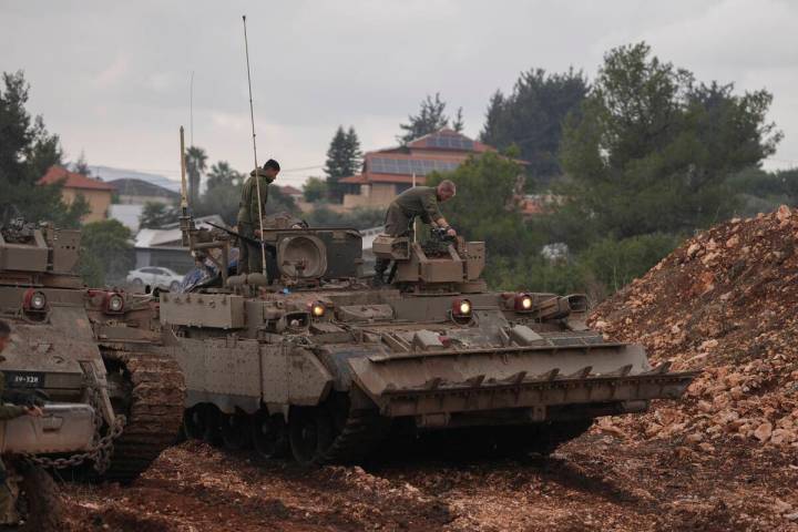 Israeli soldiers stand atop army armoured vehicles outside the agricultural settlement of Avivi ...