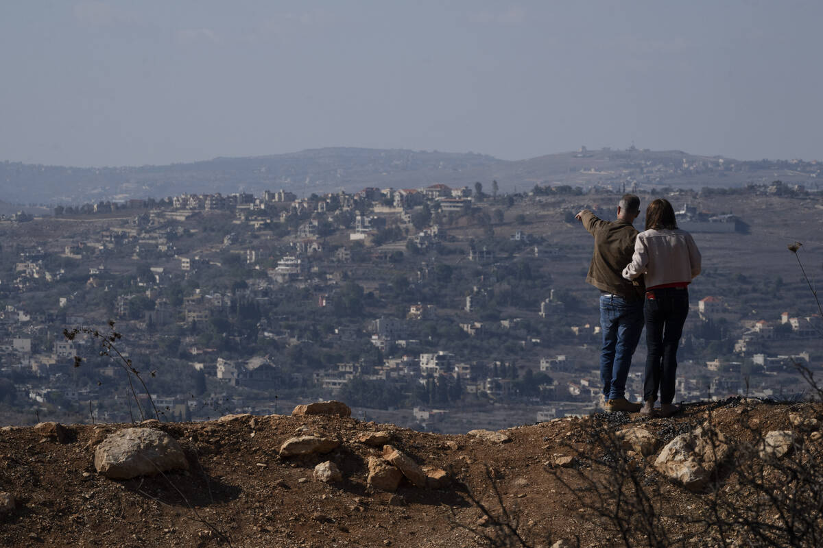 An Israeli couple observe the damaged buildings on a village in southern Lebanon as they stand ...