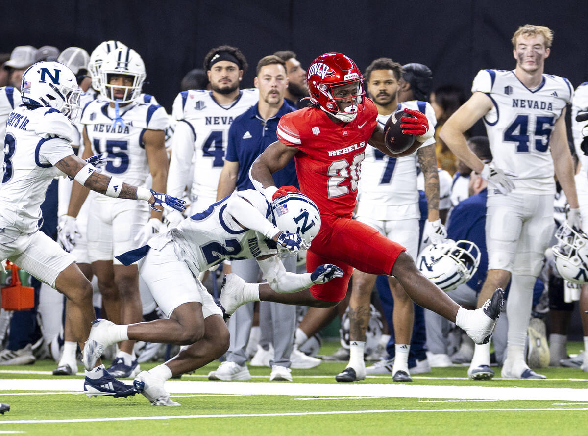 UNLV running back Kylin James (20) avoids UNR tacklers during the NCAA college football game at ...