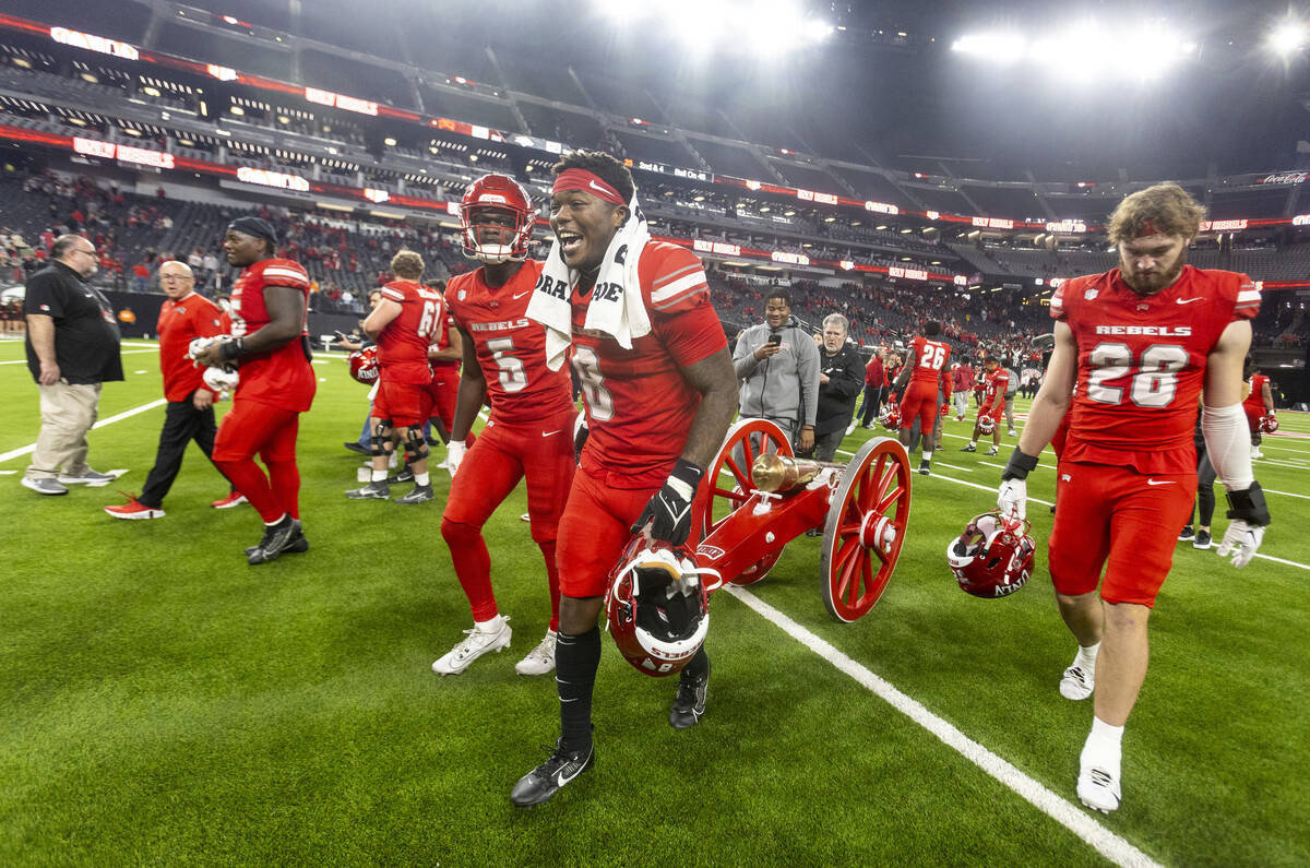 UNLV running back Greg Burrell (5) and linebacker Marsel McDuffie (8) wheel the Fremont Cannon ...