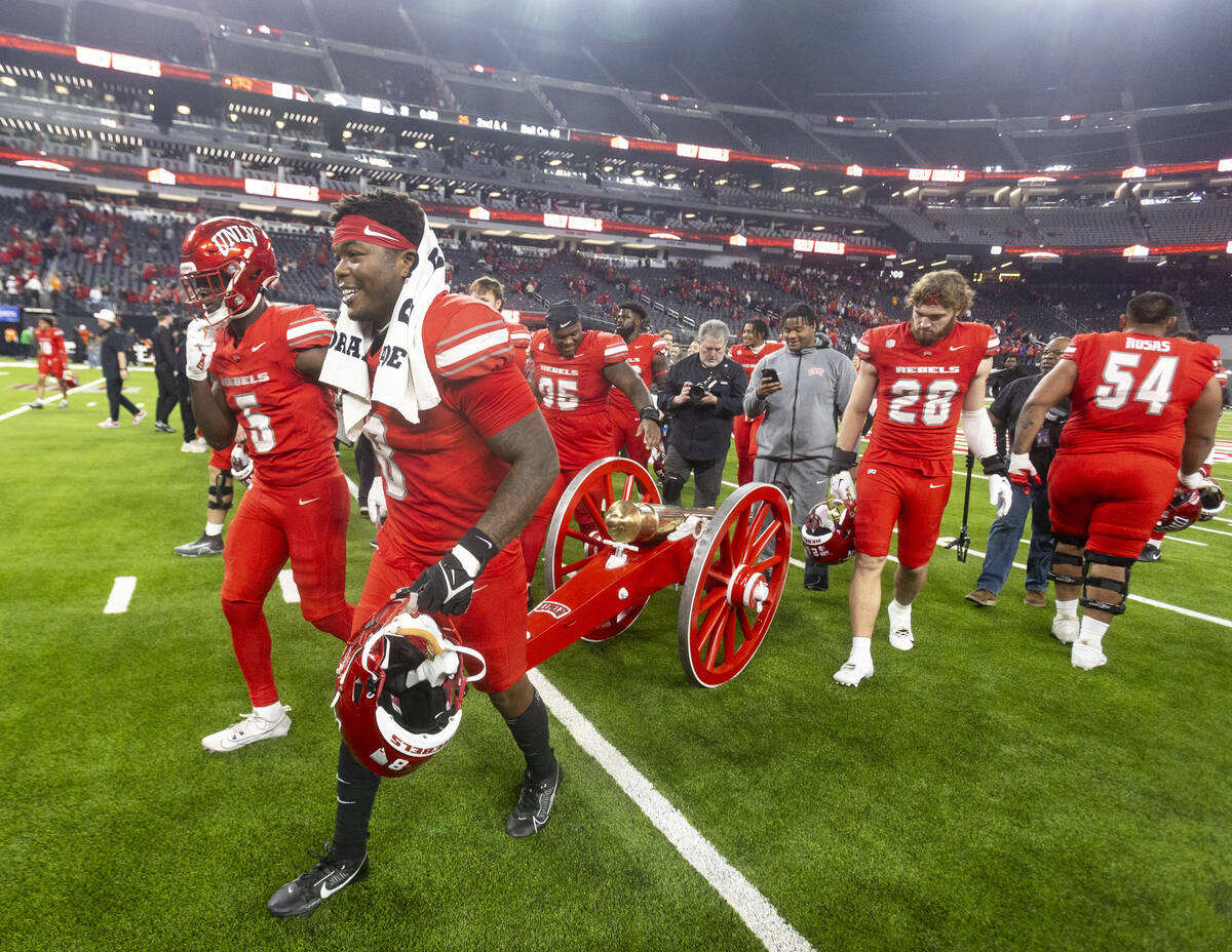 UNLV running back Greg Burrell (5) and linebacker Marsel McDuffie (8) wheel the Fremont Cannon ...