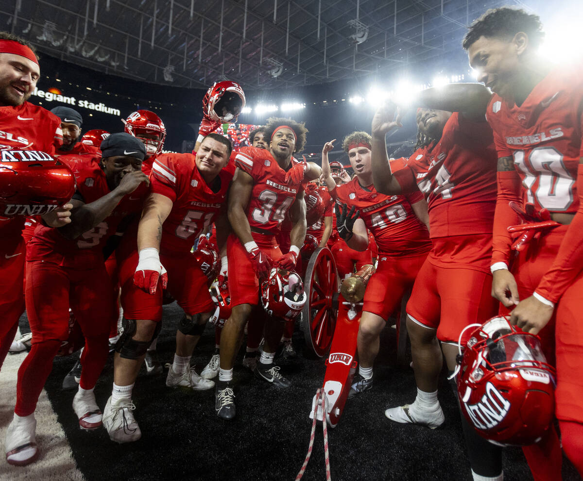 UNLV players dance with the Fremont Cannon after winning the NCAA college football game against ...