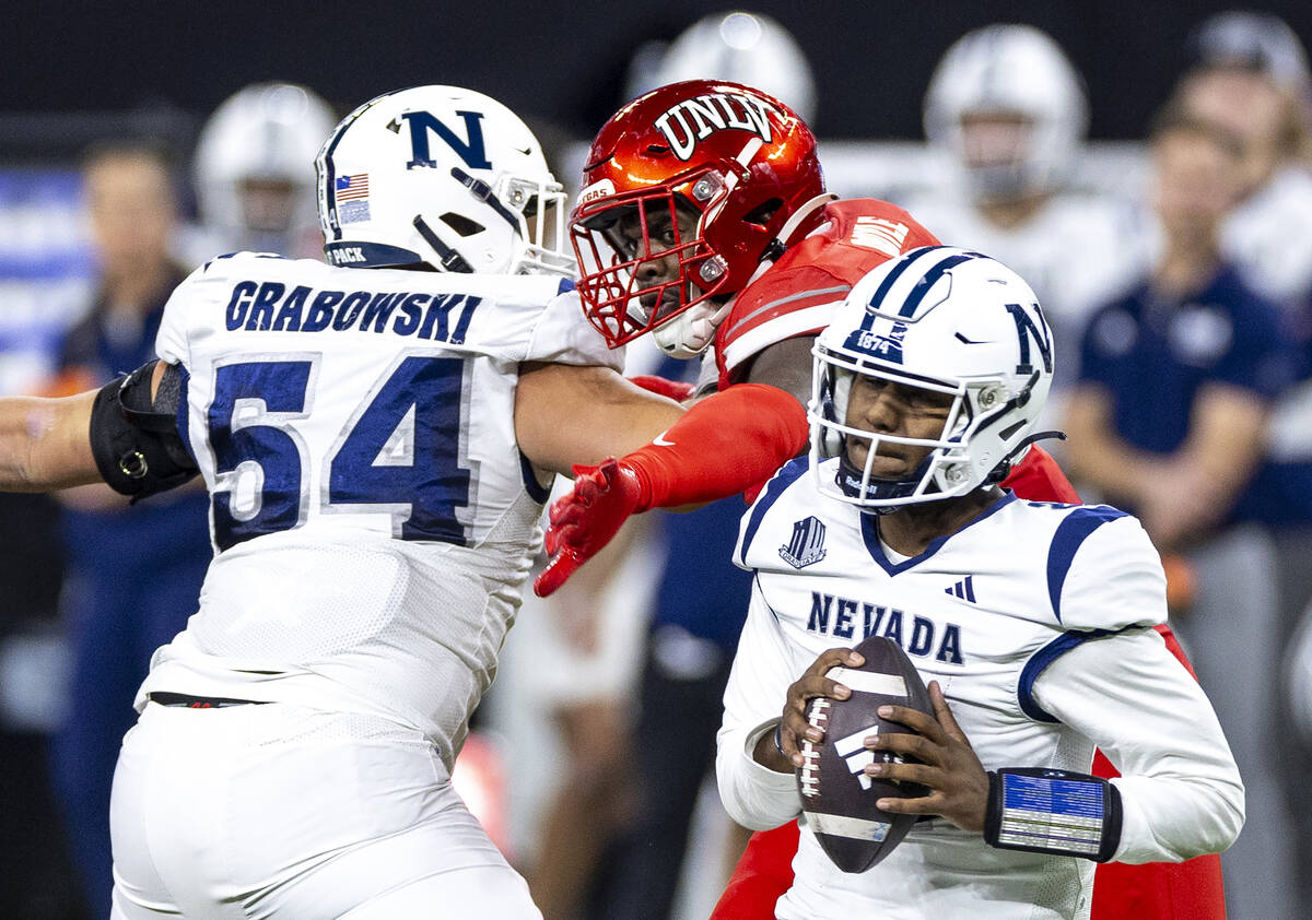 UNLV defensive end Antonio Doyle Jr., center, attempts to block UNR quarterback Brendon Lewis, ...