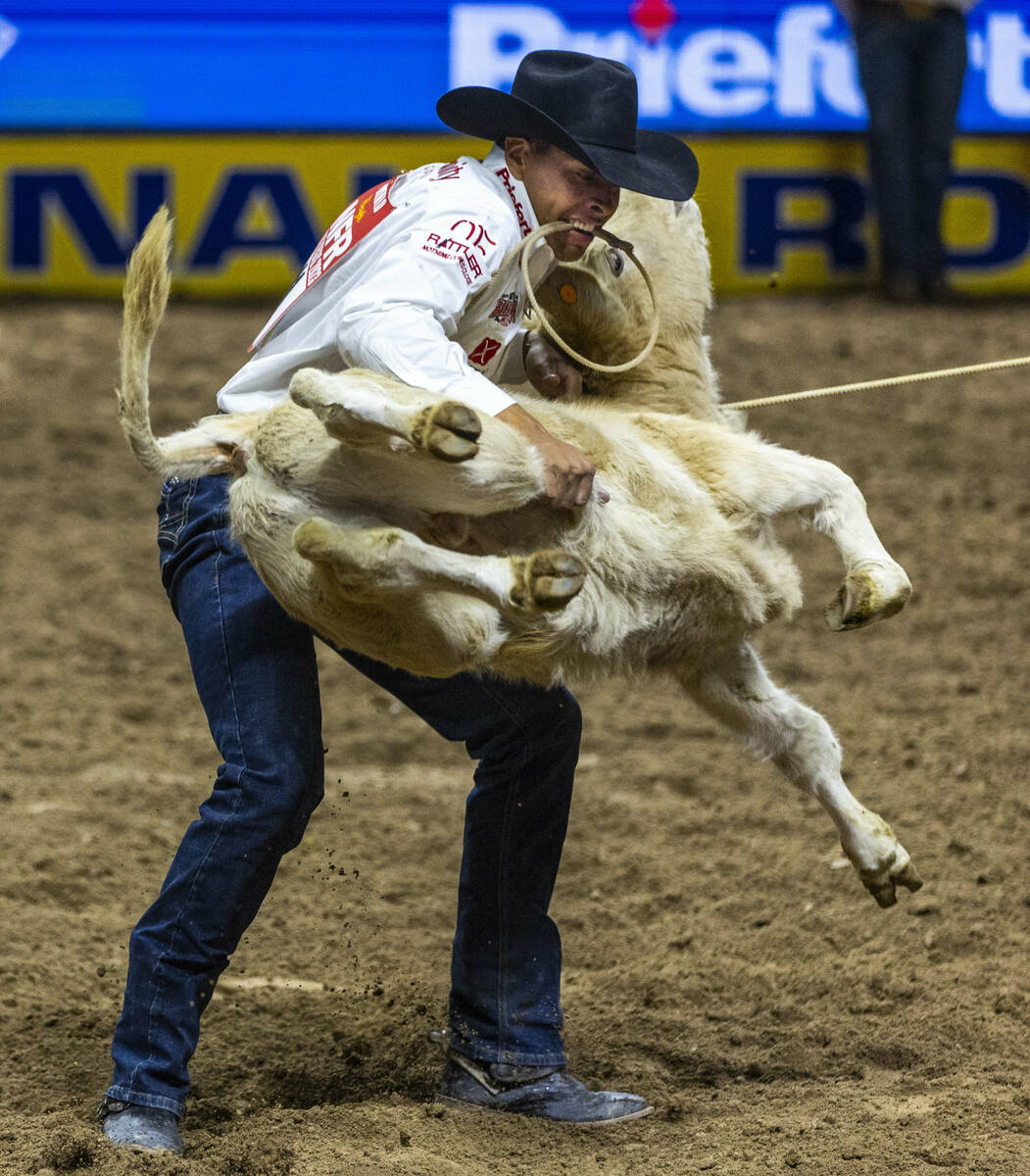 Shad Mayfield hoists his calf in Tie-Down Roping during day 6 action of the NFR at the Thomas & ...