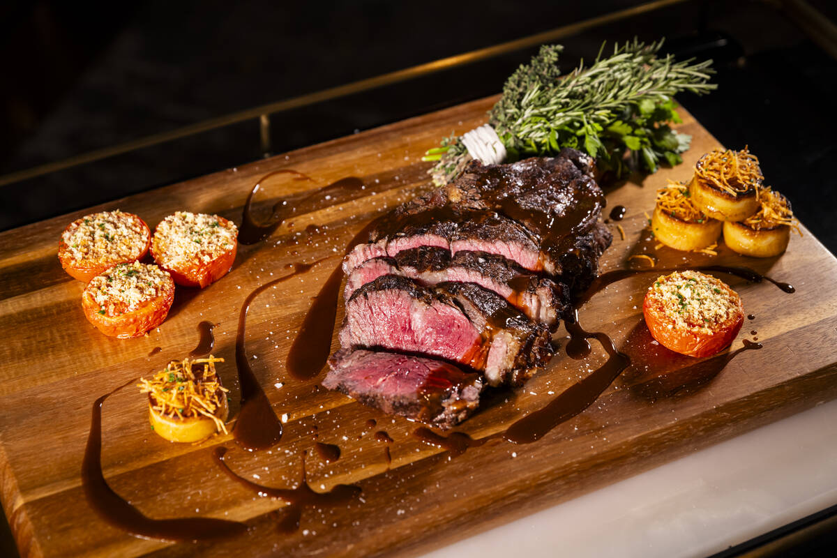 A salt-baked, hay-smoked tomahawk steak with potato crusted fondant potatoes is seen at Bourbon ...