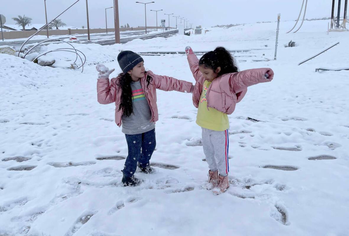 Kelly Sanchez, 7, left, and her sister Kyara, 5, play in freshly fallen snow at the intersectio ...