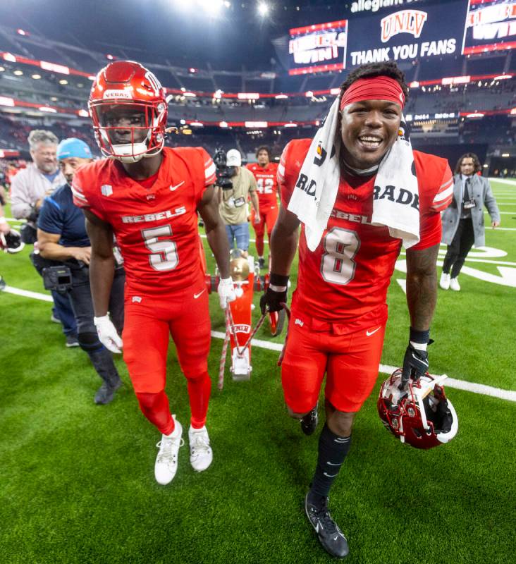 UNLV running back Greg Burrell (5) and linebacker Marsel McDuffie (8) wheel the Fremont Cannon ...