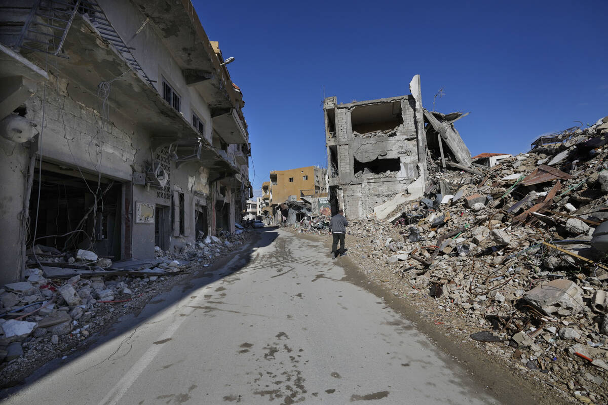 A man walks in a street between destroyed buildings as he returns to Qana village, southern Leb ...