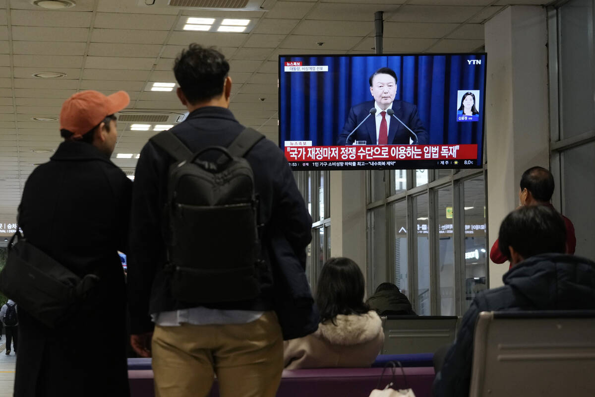 People watch a TV screen showing South Korean President Yoon Suk Yeol's televised briefing at a ...