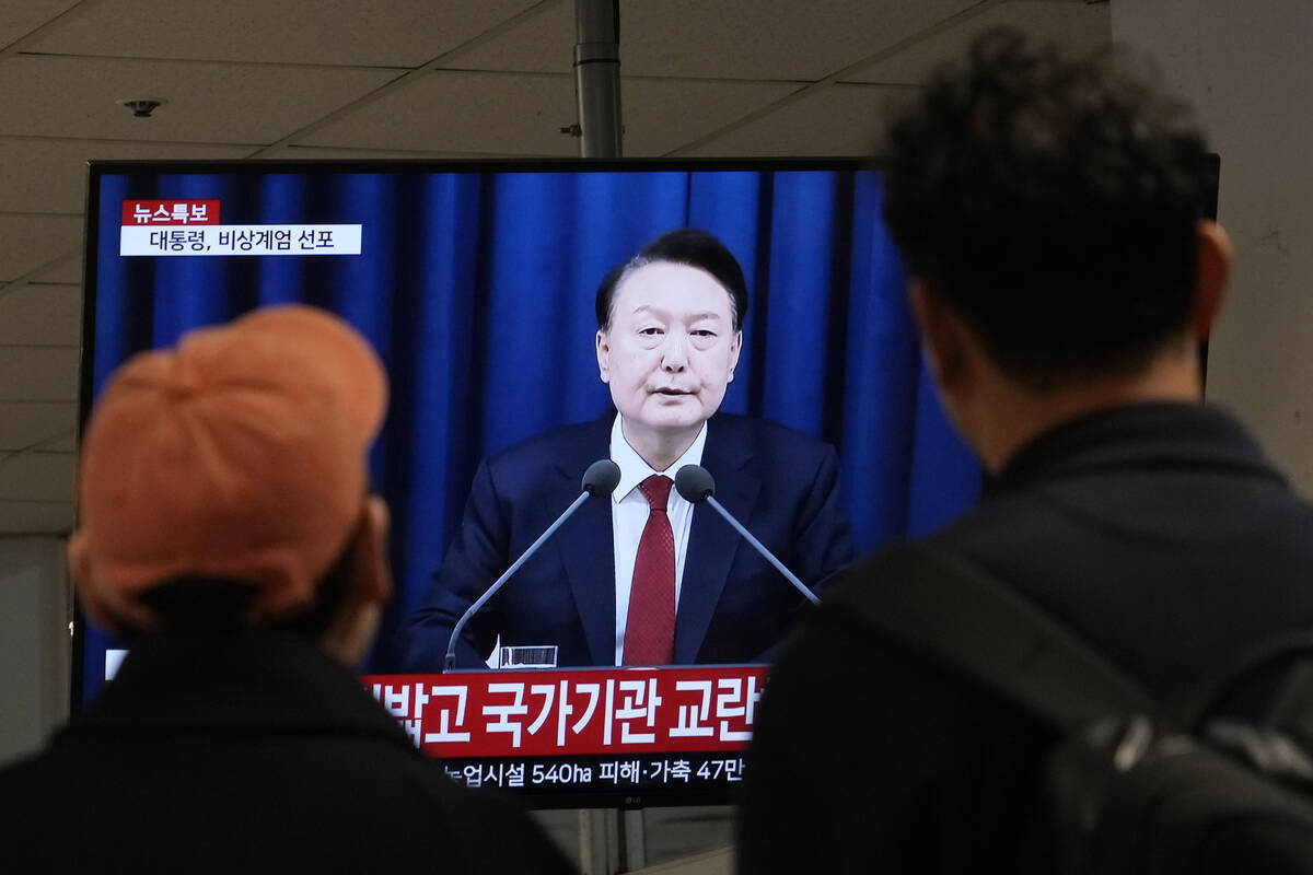 People watch a TV screen showing South Korean President Yoon Suk Yeol's televised briefing at a ...