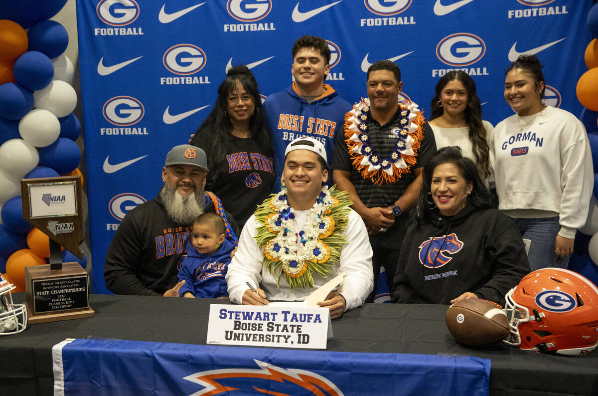 Bishop Gorman offensive lineman Stewart Taufa, center, signs a financial aid agreement with Boi ...