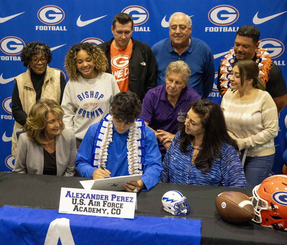 Bishop Gorman defensive back Alexander Perez, center, signs a financial aid agreement with the ...