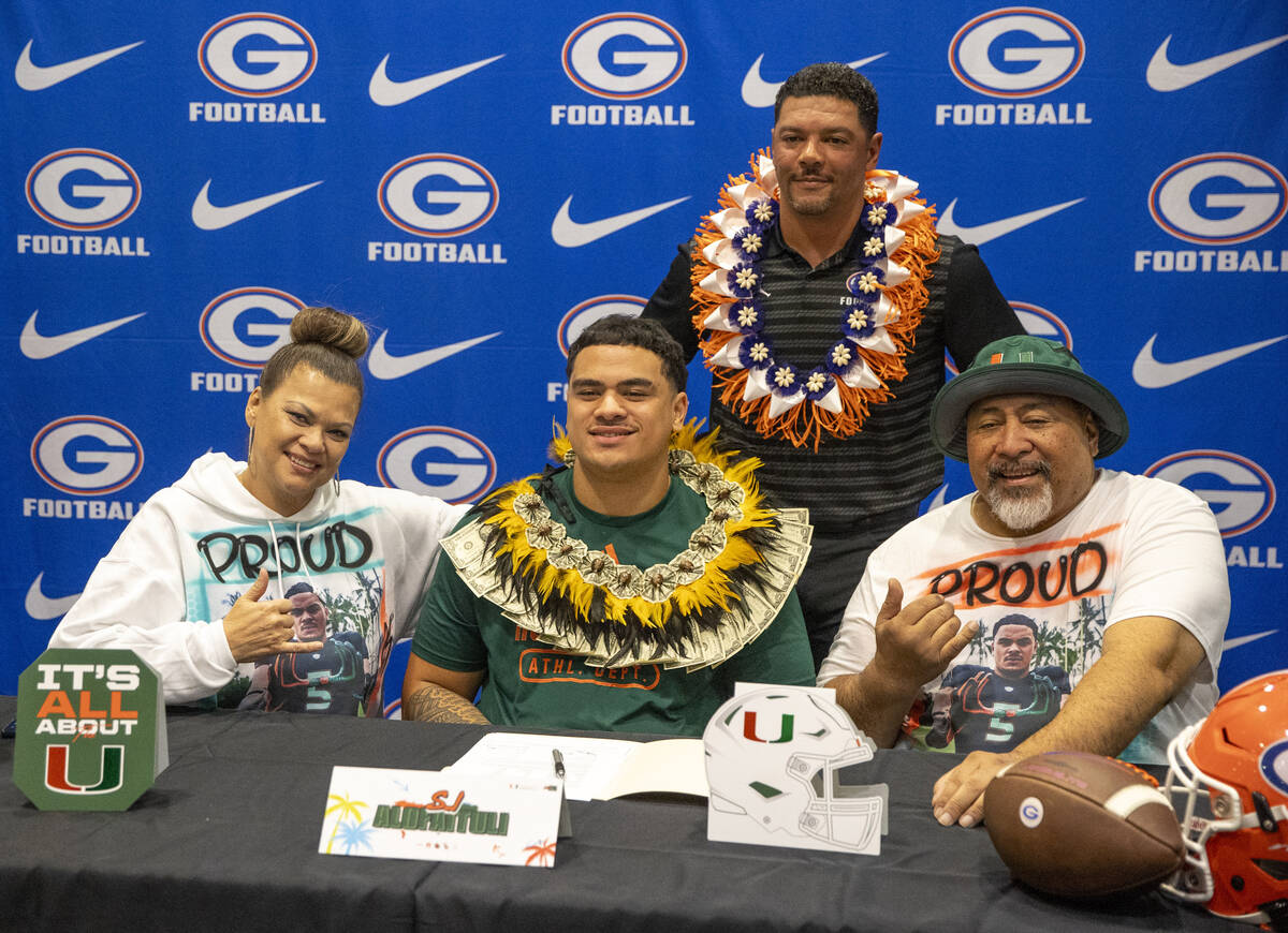 Bishop Gorman offensive lineman SJ Alofaituli, center, signs a financial aid agreement with the ...