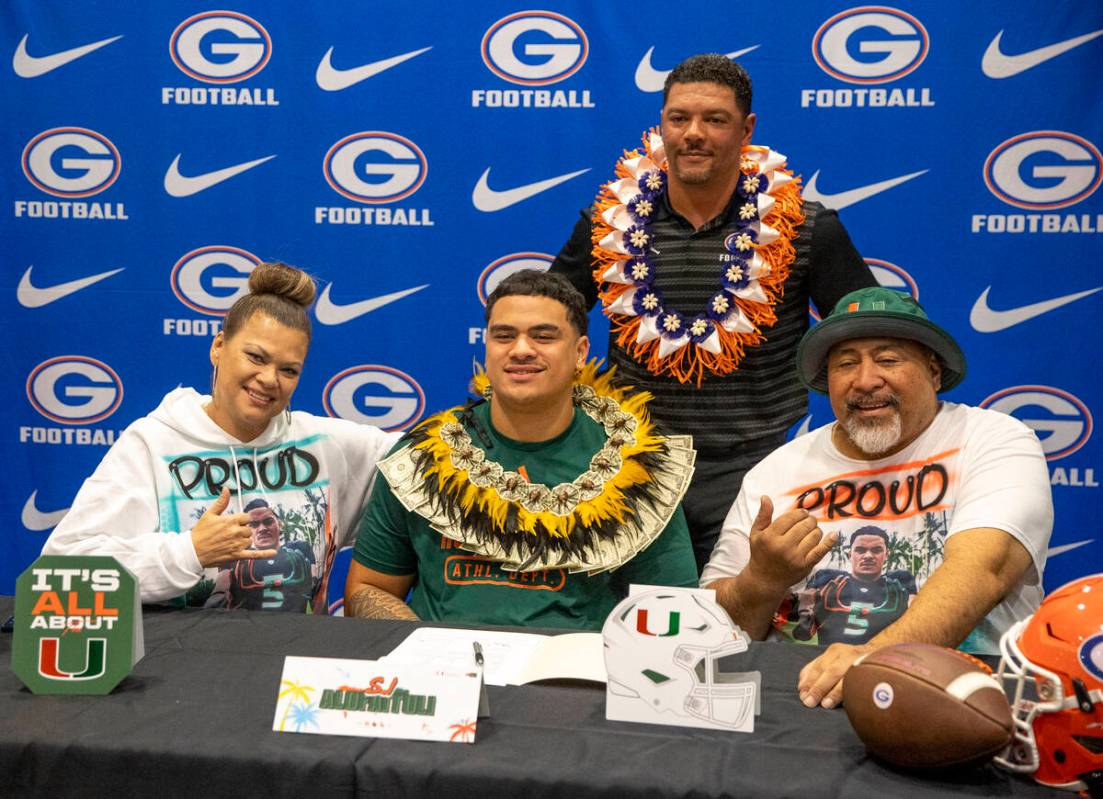 Bishop Gorman offensive lineman SJ Alofaituli, center, signs a financial aid agreement with the ...