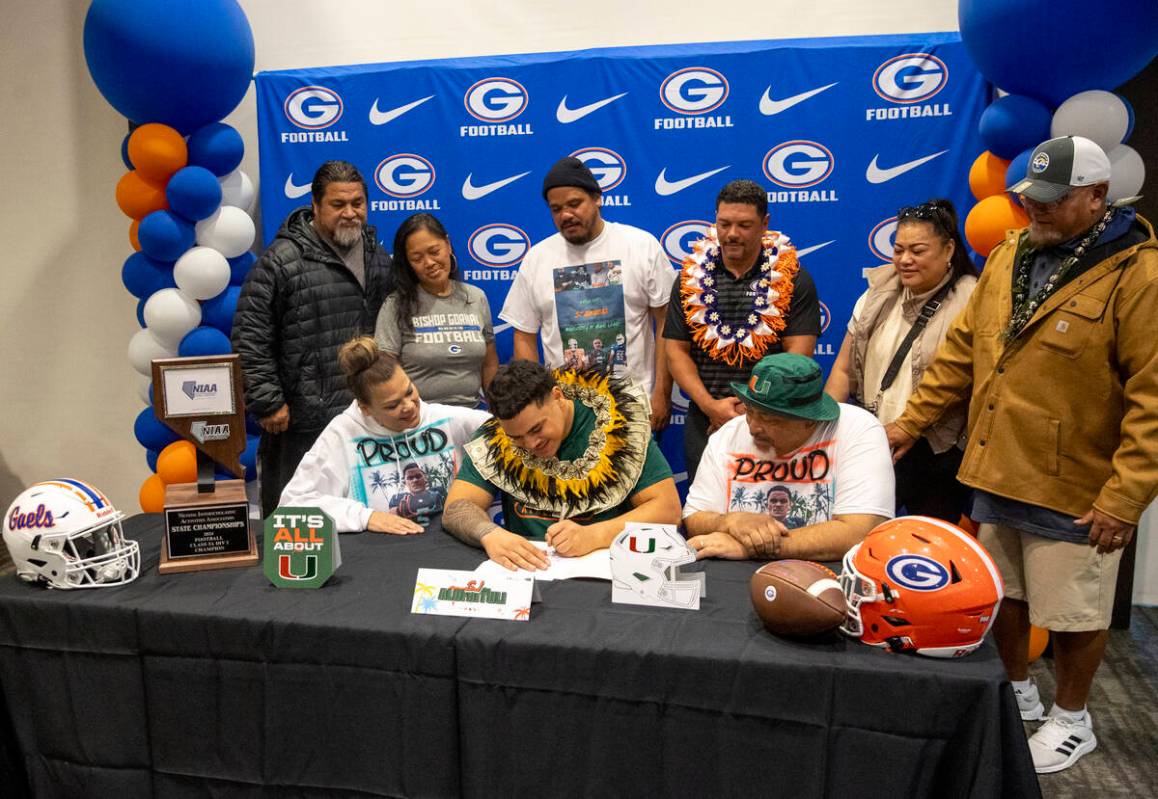 Bishop Gorman offensive lineman SJ Alofaituli, center, signs a financial aid agreement with the ...