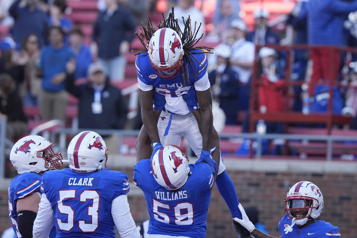 SMU wide receiver Derrick McFall (20) is lifted by teammate defensive end Isaiah Smith (58) aft ...