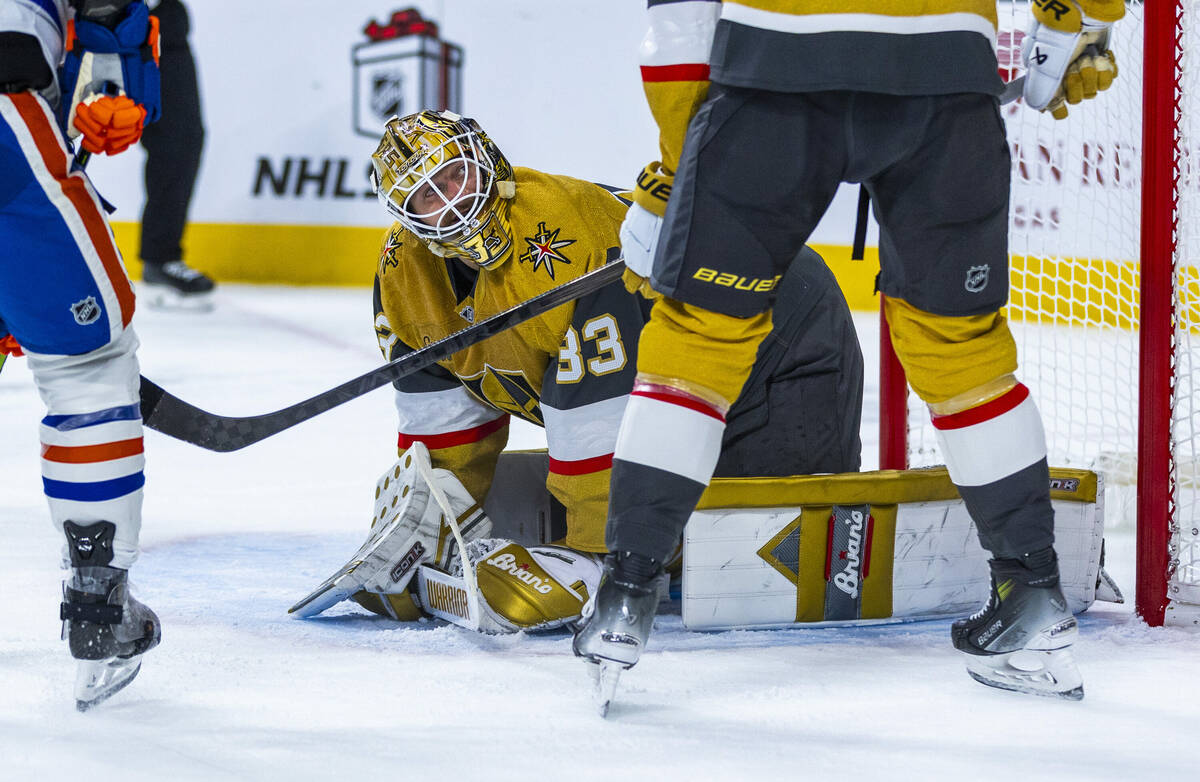 Golden Knights goaltender Adin Hill (33) looks up to teammate defenseman Shea Theodore (27) aft ...