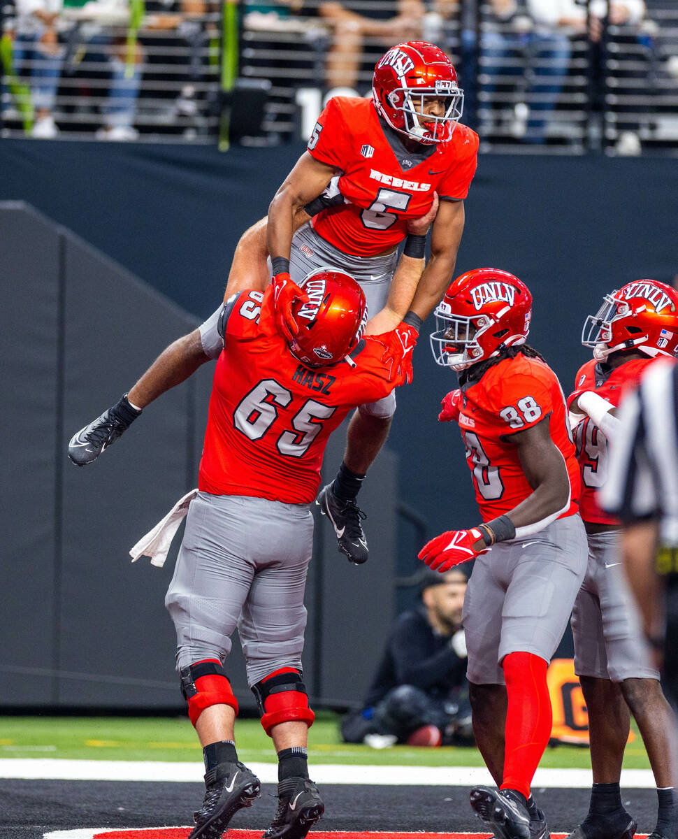 UNLV running back Vincent Davis Jr. (5) is lifted by offensive lineman Jack Hasz (65) after sco ...