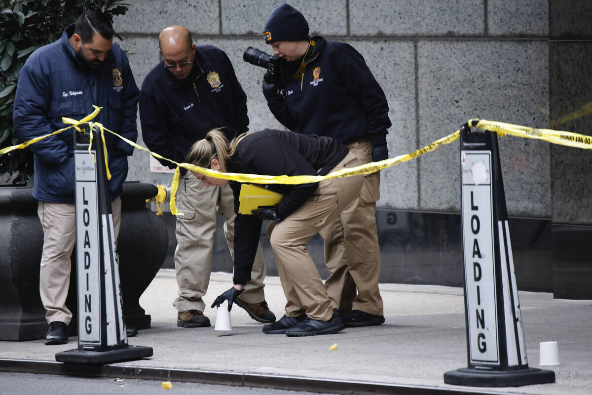 Members of the New York police crime scene unit pick up cups marking the spots where bullets li ...