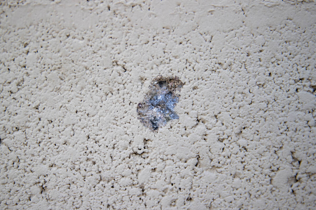 An indent from a bullet marks a wall outside of a home at the intersection of East Hacienda Ave ...