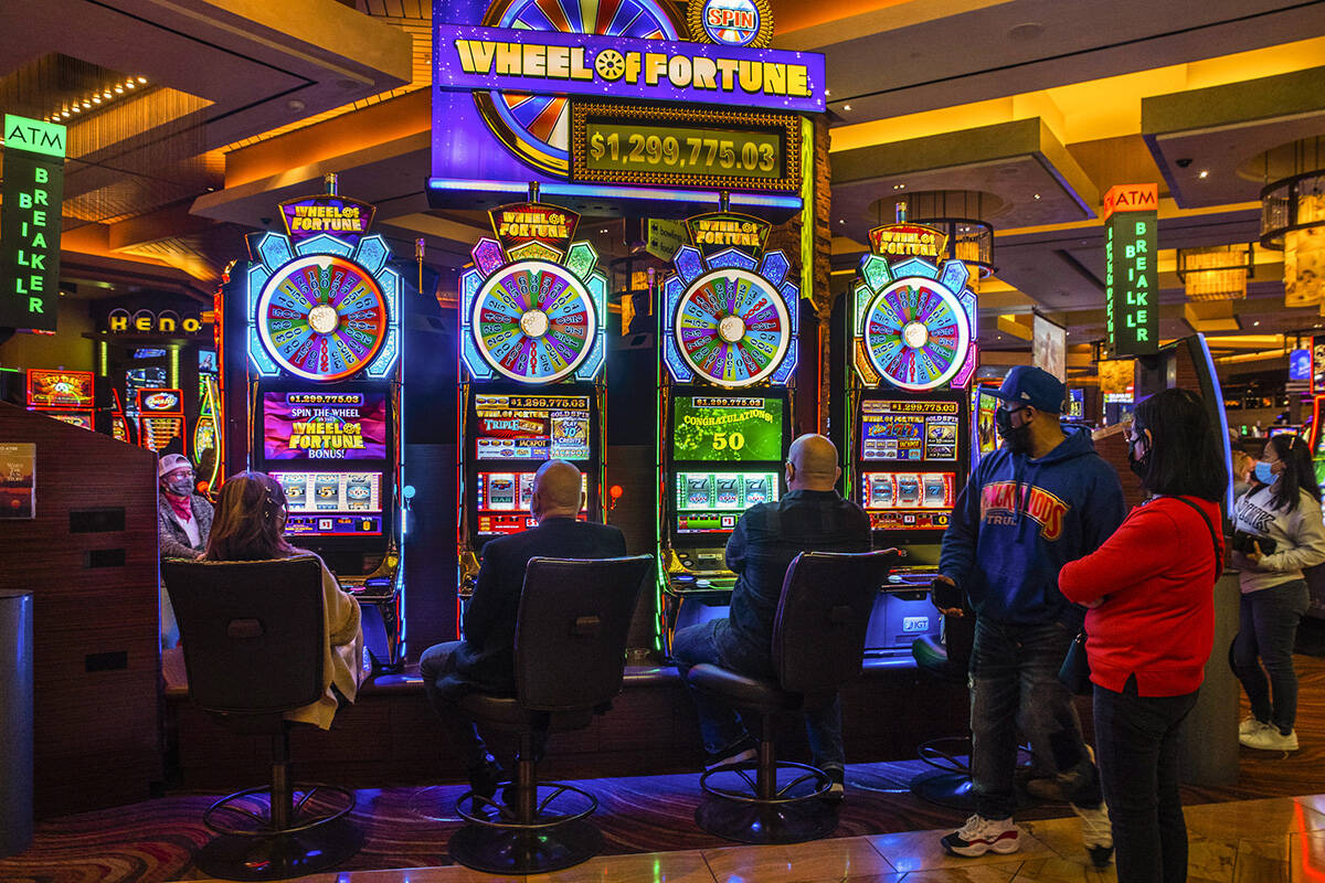 Guests play the Wheel of Fortune slots game as others watch at Red Rock Casino on Tuesday, Dec. ...