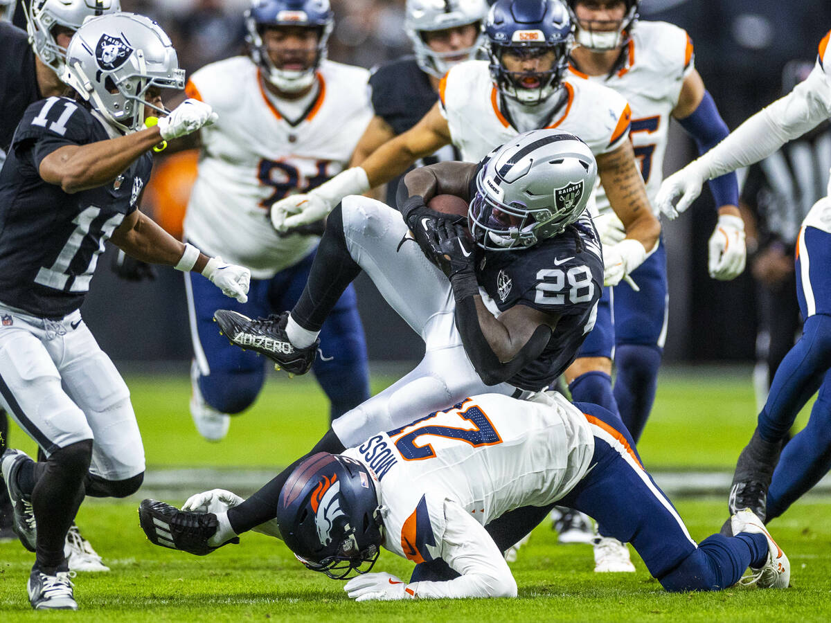 Raiders running back Sincere McCormick (28) is stopped on a run by Denver Broncos cornerback Ri ...