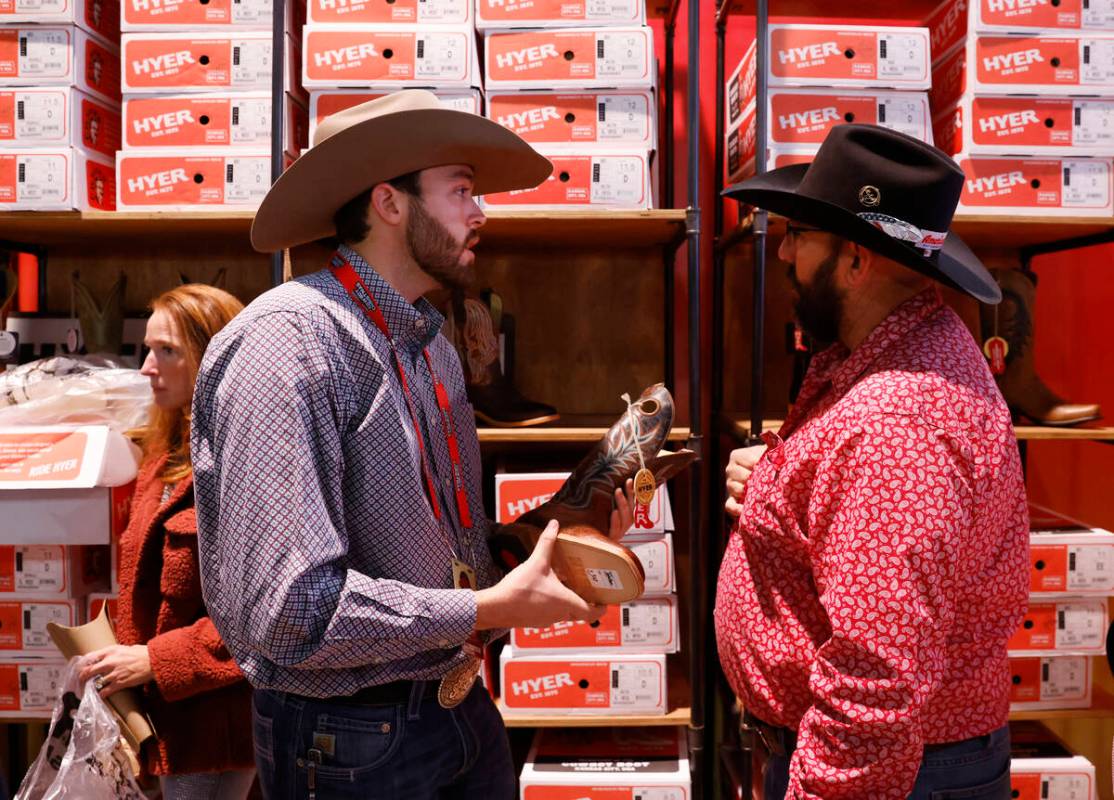 Riley Bishop, left, a sales rep, helps a customer at the Hyer boots booth at Cowboy Christmas a ...