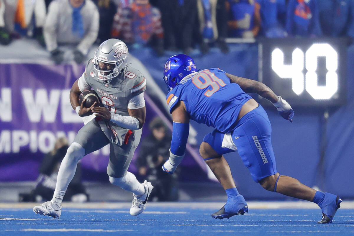 UNLV quarterback Hajj-Malik Williams (6) scrambles with the ball in front of Boise State defens ...