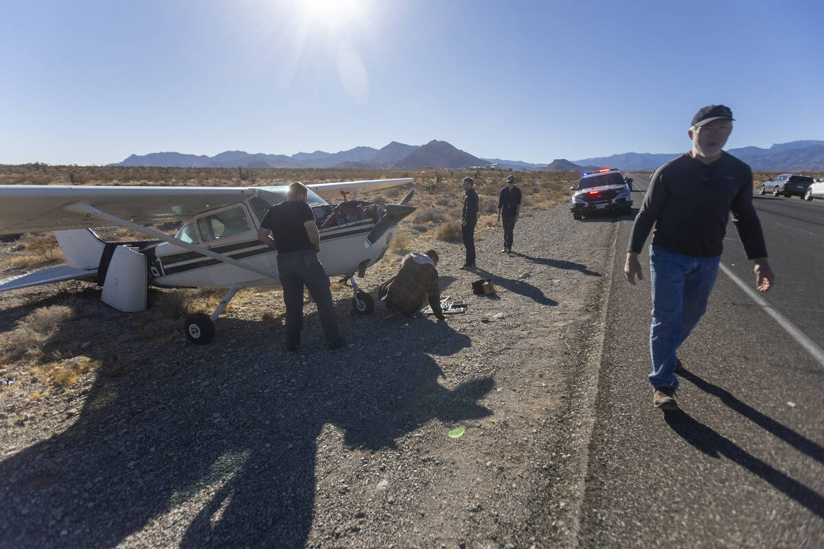 A crew of men, who declined to give their names, work on a plane after it emergency landed on K ...