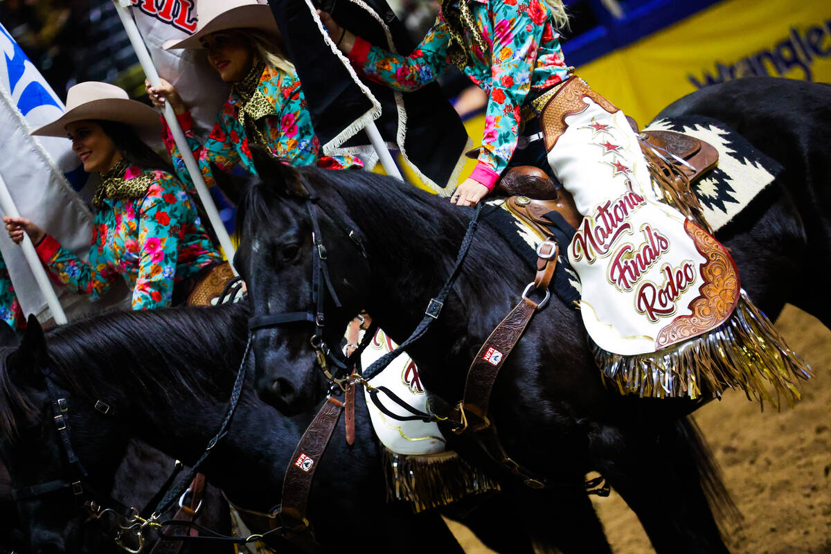 Cowgirls hold advertiser flags during round three of the National Finals Rodeo at the Thomas &a ...