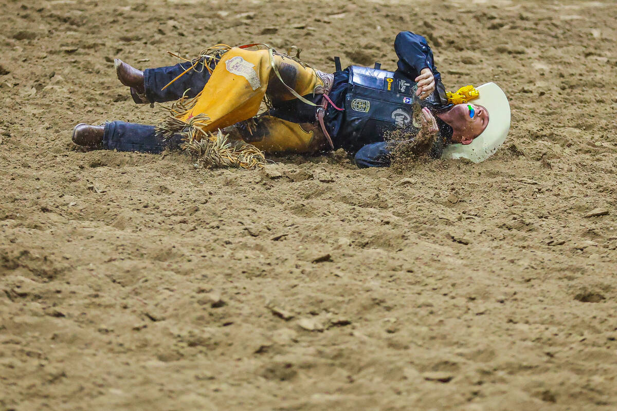 Saddle bronc rider Brody Cress falls into the dirt during round four of the National Finals Rod ...