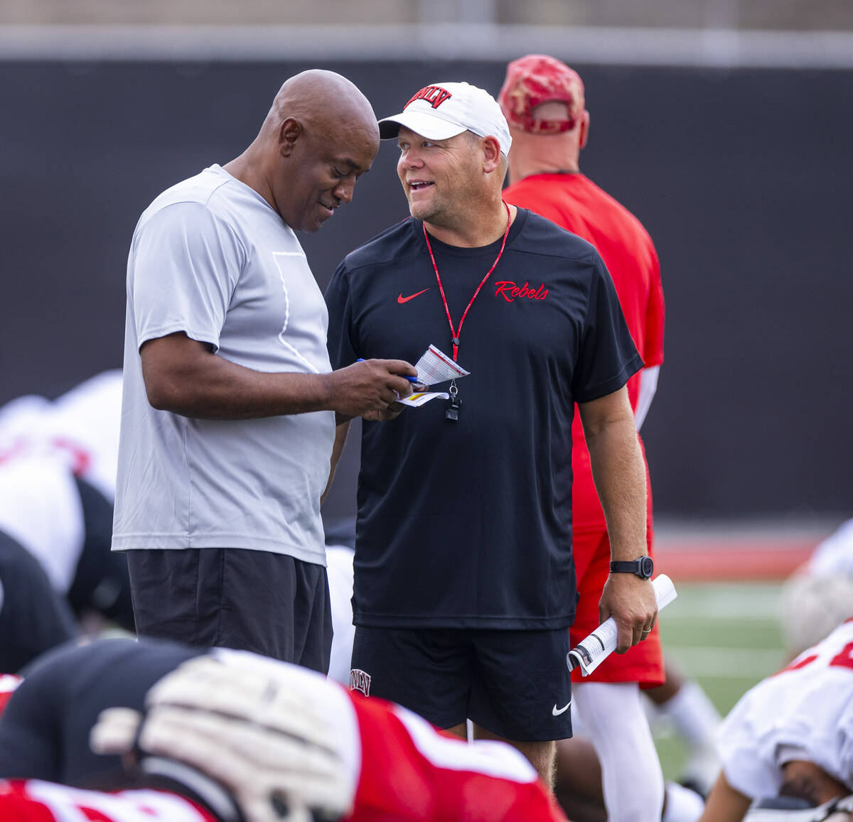 UNLV head coach Barry Odom shares a few words with wide receivers coach Del Alexander as player ...