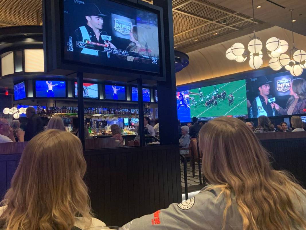 From left, Belle and Kate Lindsey take in Friday's rodeo action on one of several TVs showing t ...