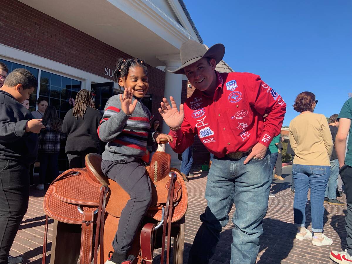 World team roping champion Tyler Wade makes sure 6-year-old Korde James is comfortable and happ ...