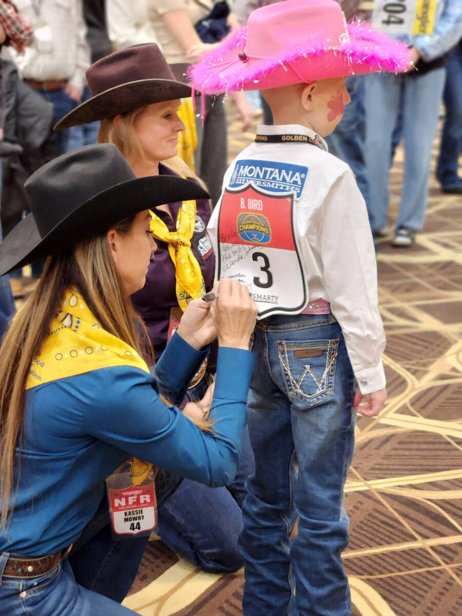 Barrel racer Kassie Mowry signs a Golden Circle child's back number, joined by fellow barrel ra ...