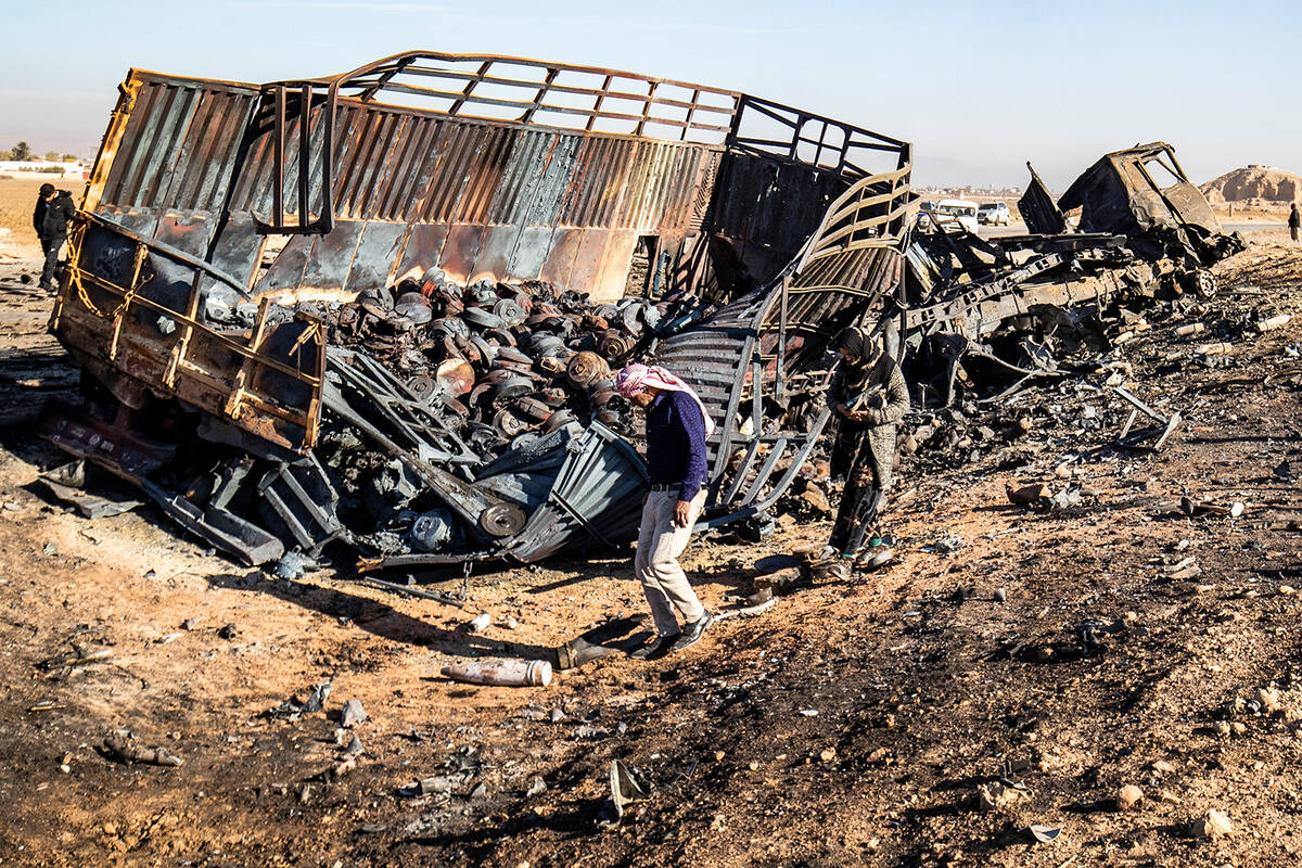 Syrians look for metal pieces and unexploded ammunition at the site of the previous evening's I ...